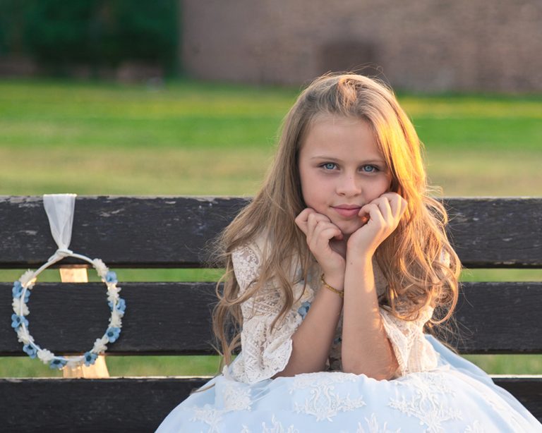 Niña en su sesión de fotos de comunión sentada en un banco de madera en un parque de Alcorcón, Madrid.