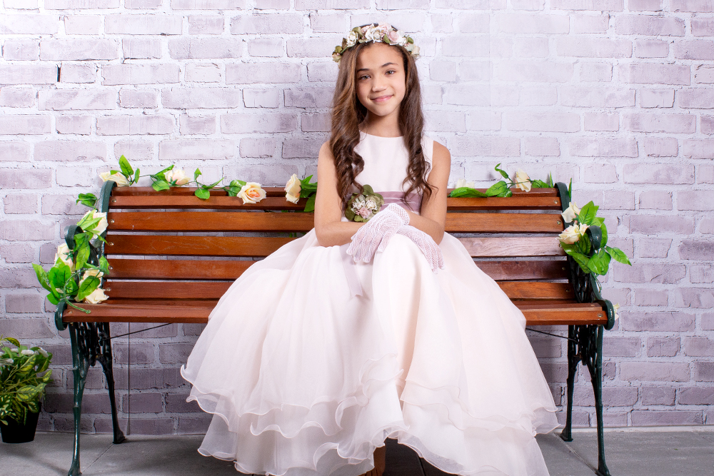 Sesión de comunión atemporal en estudio: niña con vestido, guantes y corona de flores en un banco decorado en Alcorcón.