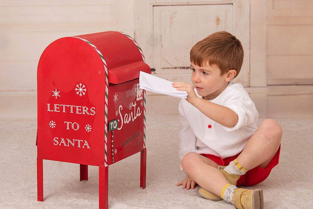 Niño pelirrojo con su carta para los regalos en el decorado navideño de nuestro estudio en Alcorcón.